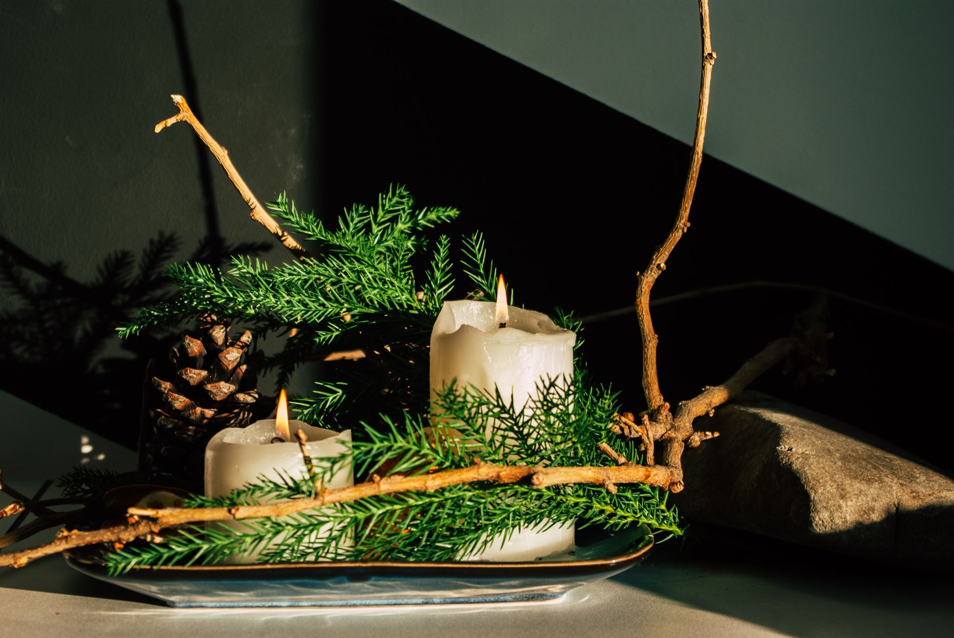 A warm candlelit setup featuring pine branches and pinecones, perfect for holiday decor.