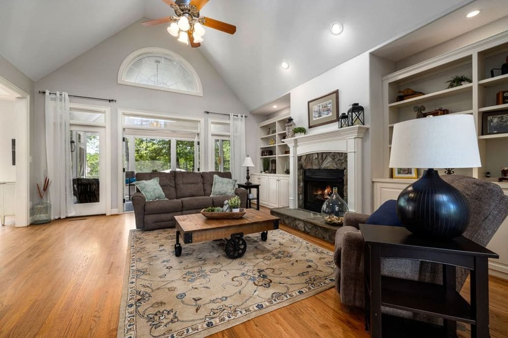 Spacious and elegant living room featuring a stylish fireplace, neutral tones, and ample natural light.