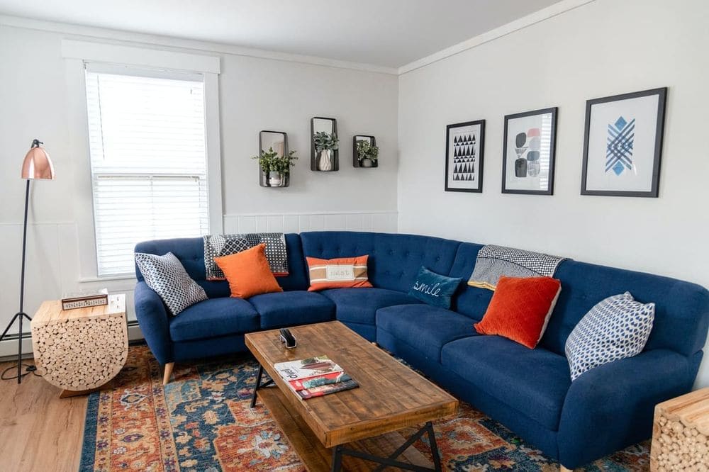 Bright and stylish living room featuring a blue sectional, vibrant pillows, and modern decor.