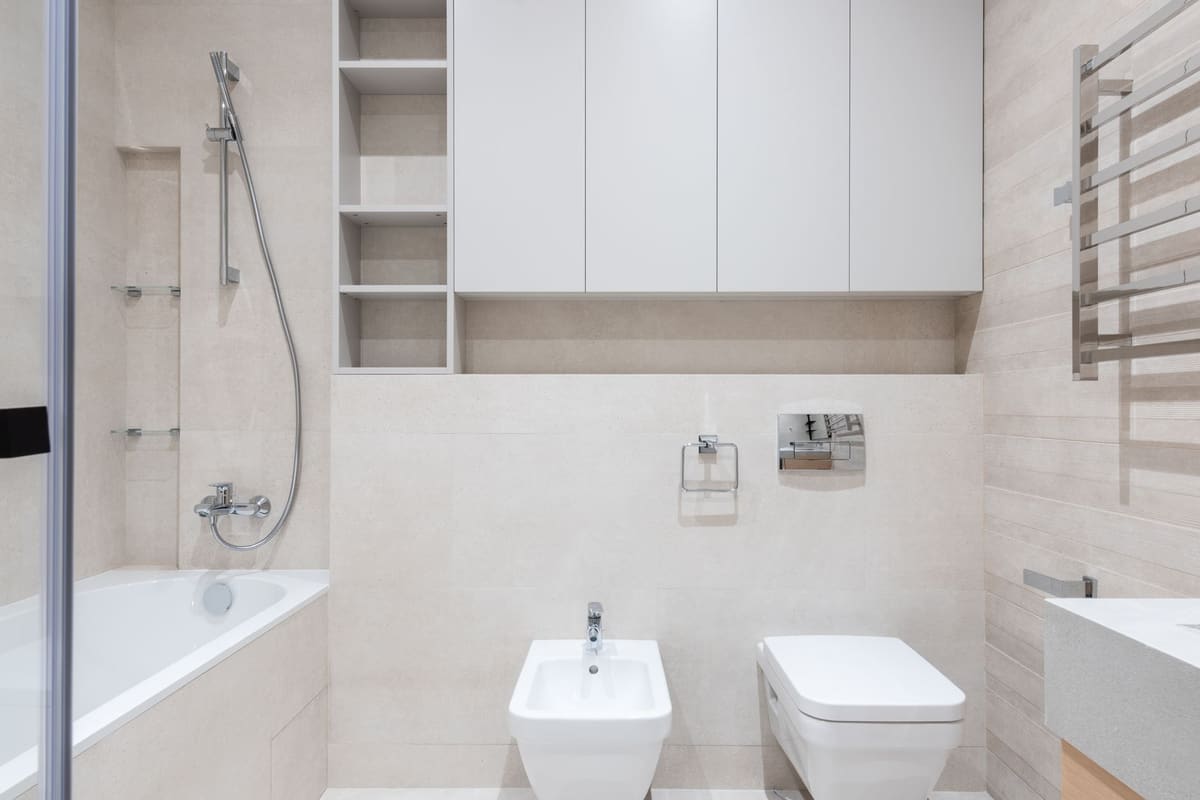 Interior of modern light bathroom with bidet and toilet next to sink and bath