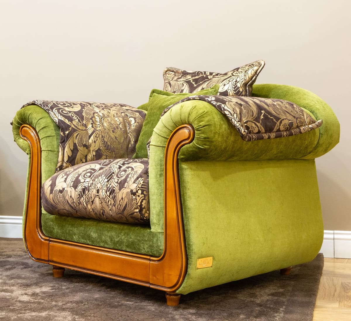 Stylish green armchair featuring luxurious fabric with intricate patterns and a vintage wooden finish.