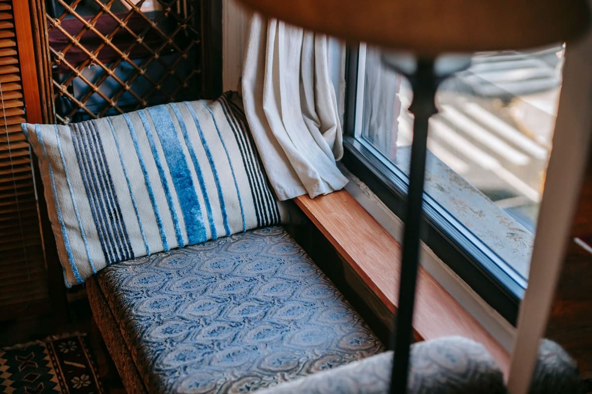 Interior of comfortable vintage room with couch and pillow under lamp near glass window