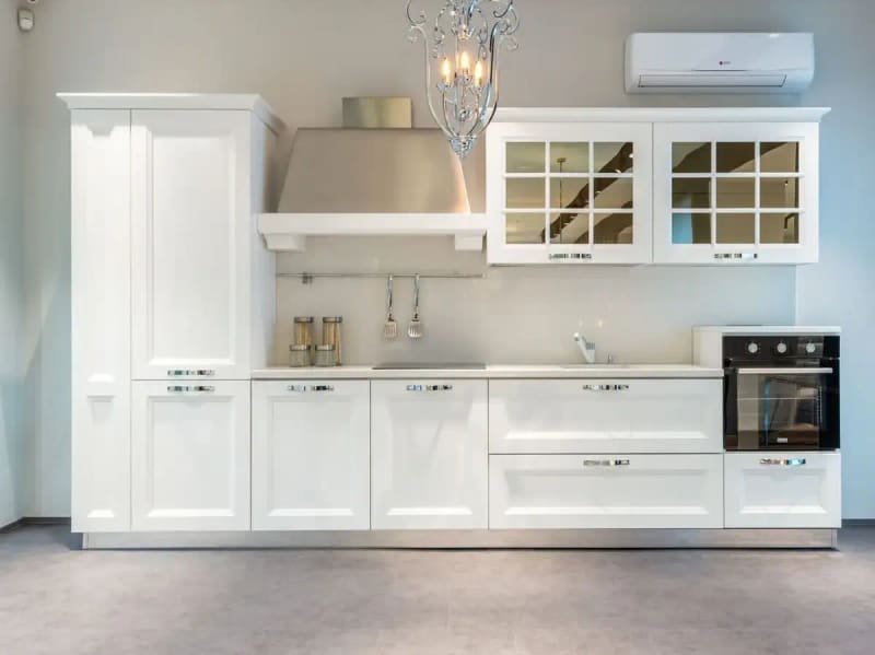 Interior of modern furnished kitchen with elegant white cabinets and contemporary appliances in spacious apartment