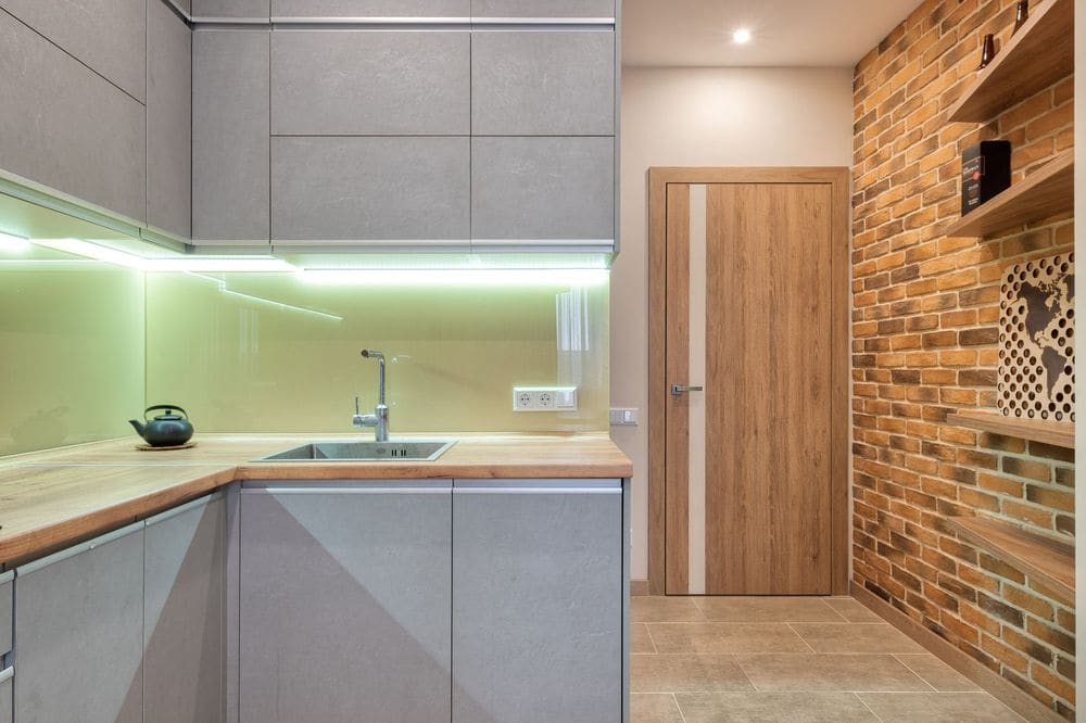 Contemporary kitchen design featuring brick wall, under-cabinet lighting, and wooden details.