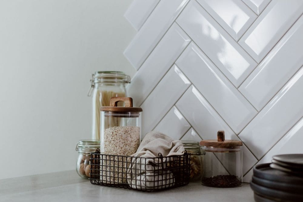 Stylish kitchen setup featuring glass jars with pasta and grains on a clean counter.