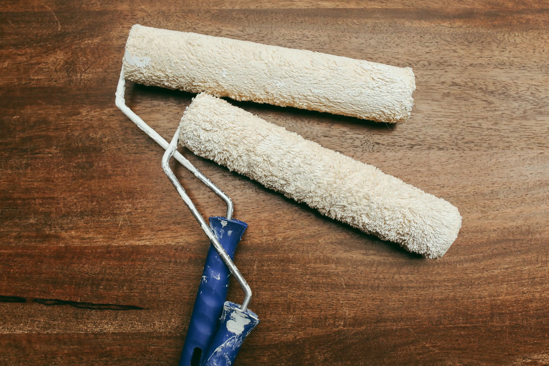 Two paint rollers over a wooden surface, perfect for home renovation concepts.