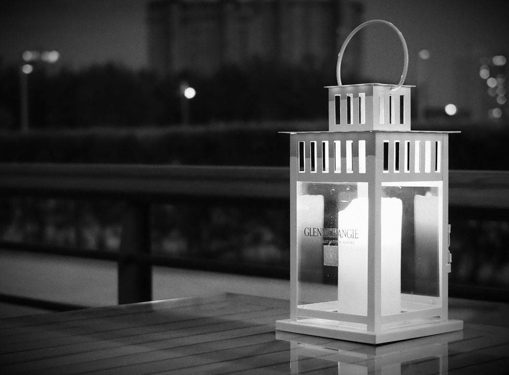 Elegant white lantern glowing outdoors in a peaceful evening setting, creating a warm ambiance.
