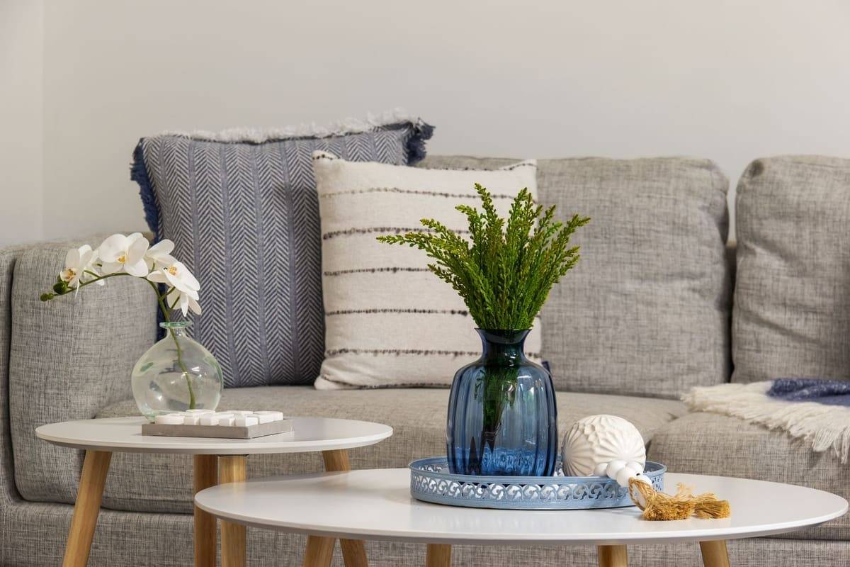 Stylish grey sofa and coffee table arrangement with blue vase and cushions for a modern minimalist interior.