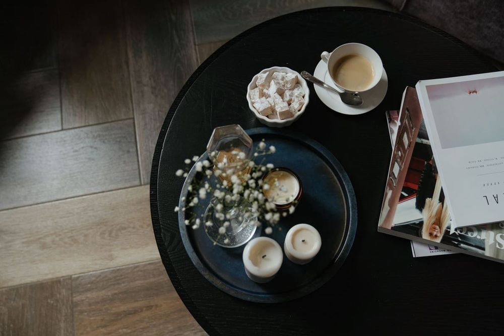 A serene coffee break setting with books, candles, and sweet treats on a round table.