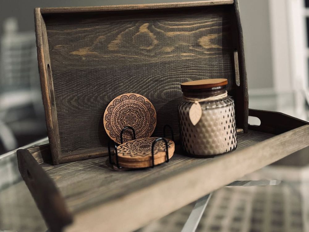 Wooden tray featuring rustic coasters and a decorative candle jar for home decor.