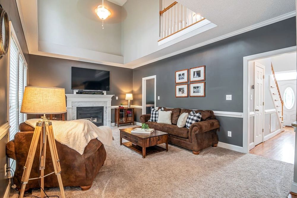 Spacious and elegant living room featuring a cozy fireplace, modern furniture, and warm lighting.