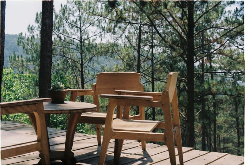 Wooden patio with chairs and table overlooking a lush forest, perfect for relaxation.