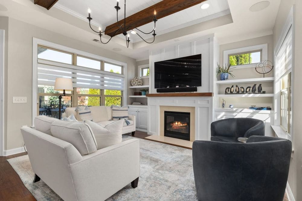 A cozy, modern living room featuring a fireplace, large TV, and stylish seating arrangements.