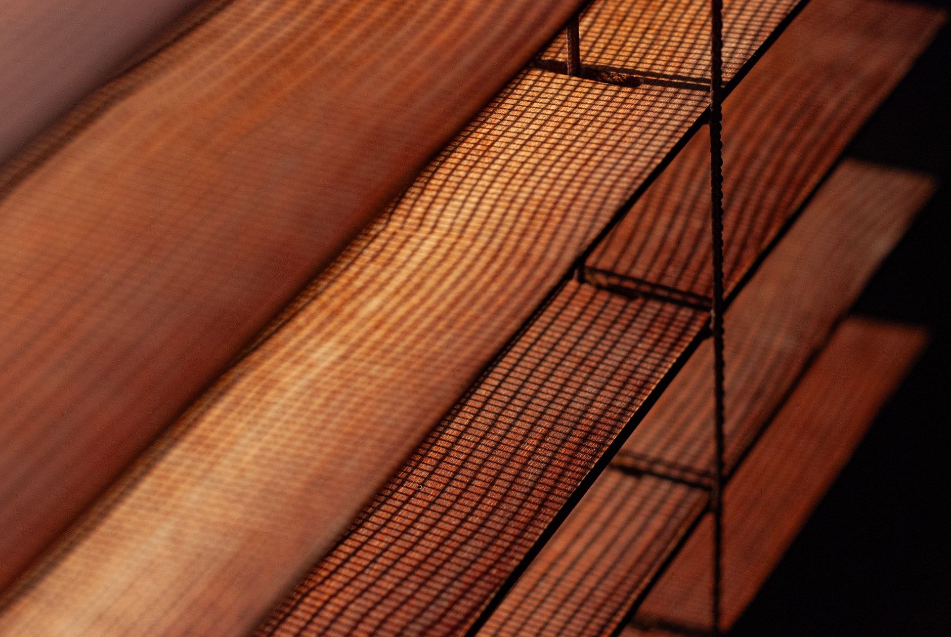 Detailed view of brown mesh blinds with warm lighting, creating a cozy indoor ambiance.