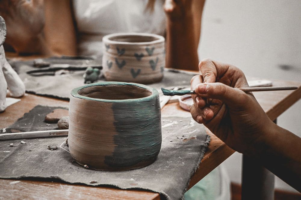 Close-up of hands skillfully painting pottery, capturing creativity and craftsmanship at work.