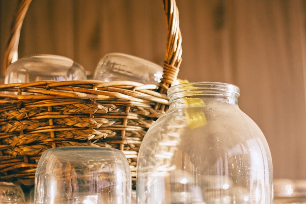 A wicker basket filled with glass jars, warmly lit, capturing a cozy rustic feel.