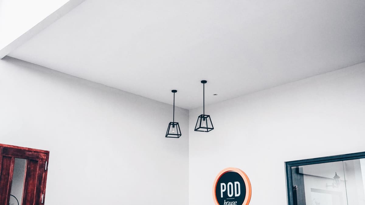 Modern minimalist interior featuring geometric pendant lights and a POD sign.