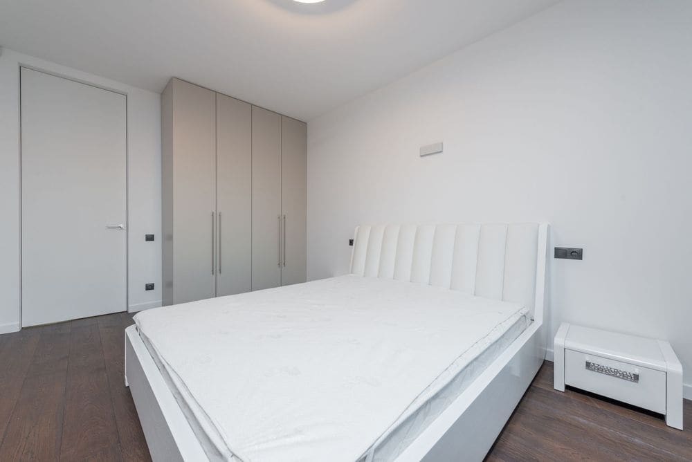Bright minimalist bedroom featuring a white bed and contemporary design.