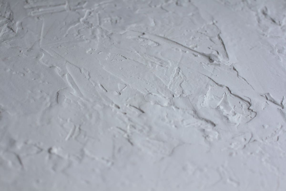 Close-up shot of a textured white plaster surface with rough details.