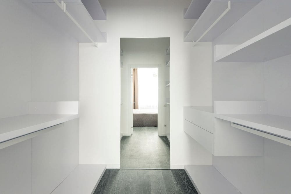 Bright and spacious modern minimalist walk-in closet with open shelving.