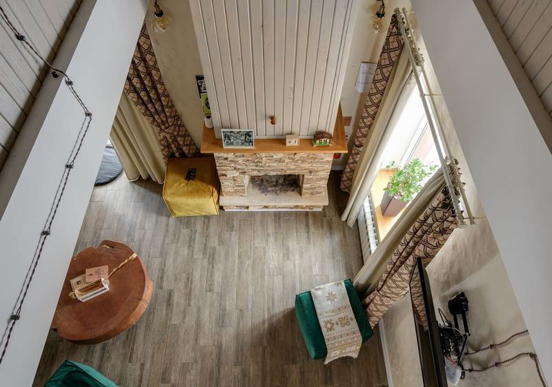 High-angle view of a stylish living room featuring a rustic fireplace and a wooden floor, showcasing modern interior design.