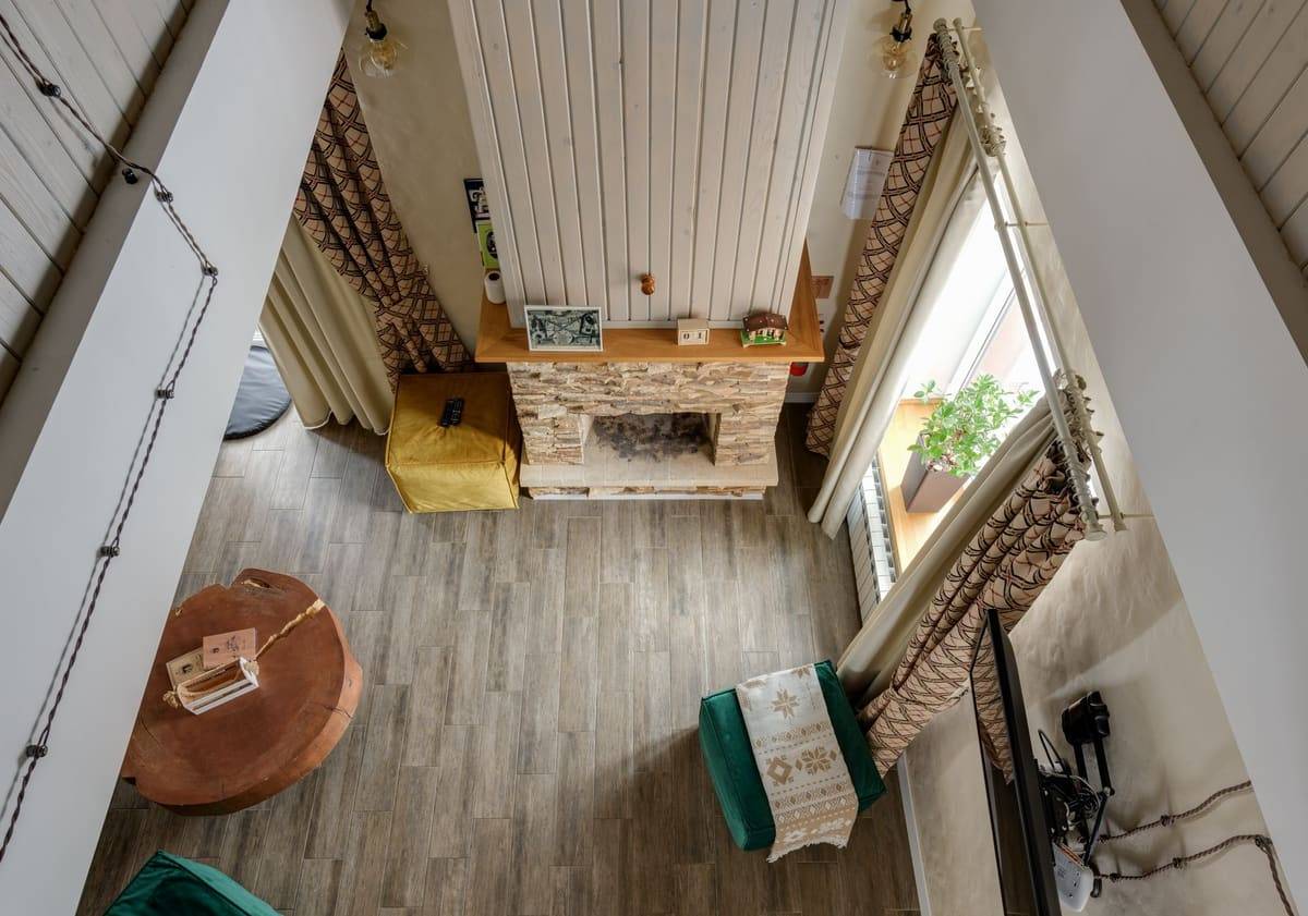 High-angle view of a stylish living room featuring a rustic fireplace and a wooden floor, showcasing modern interior design.