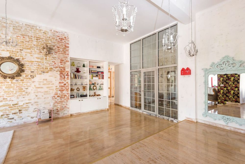 Bright room featuring a brick wall, chandeliers, mirrored frames, and bookshelves.