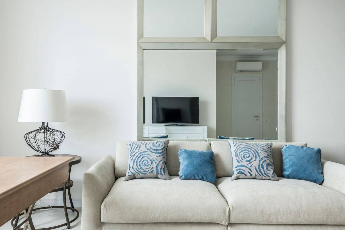 Interior of cozy living room with comfortable sofa with soft cushions placed near table with lamp