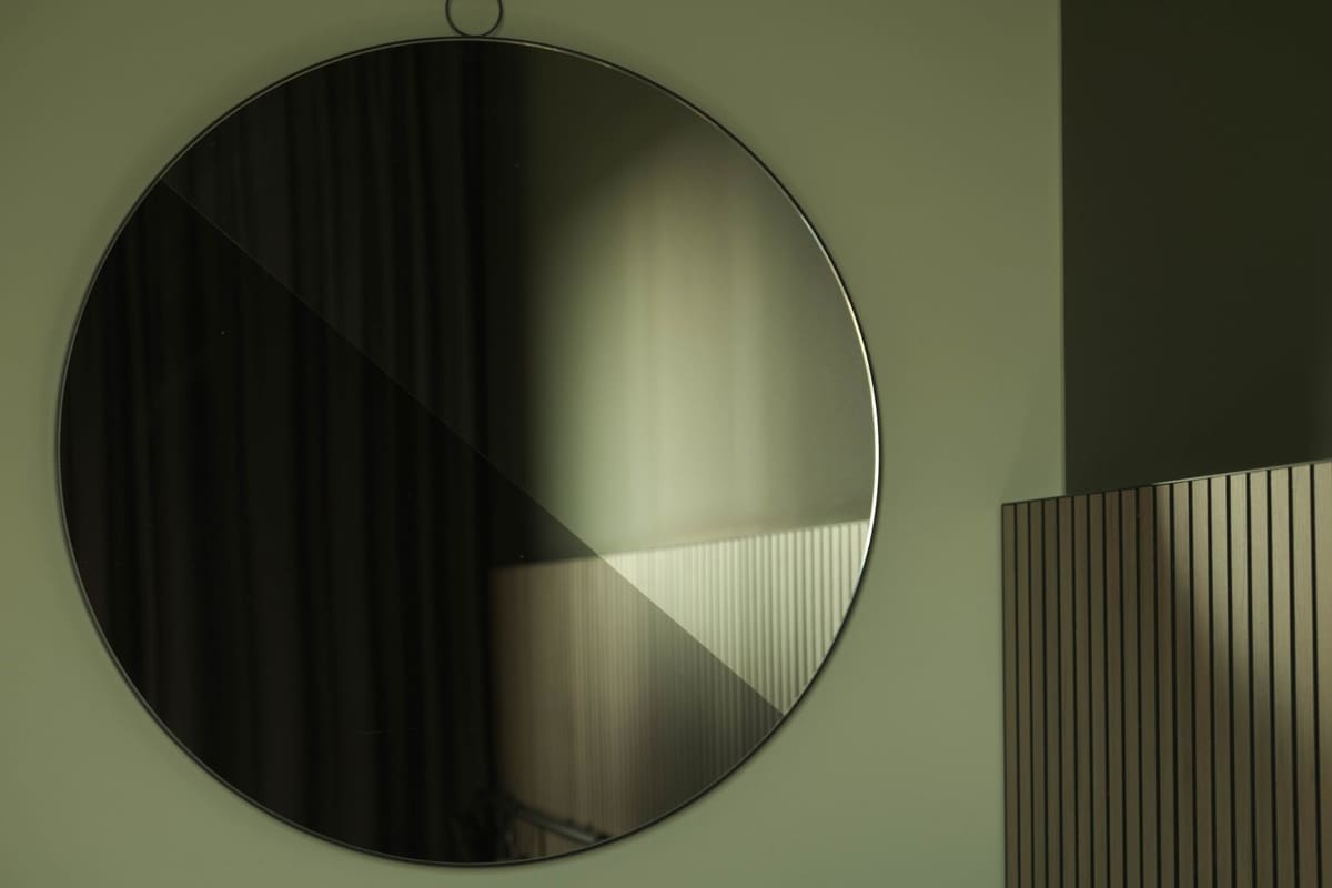 A large circular mirror reflecting soft light in a modern interior.