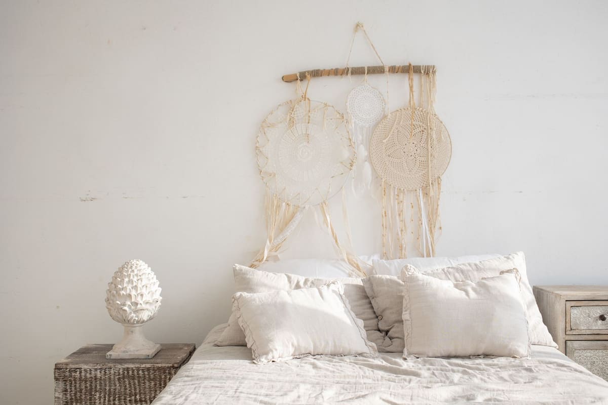 Charming rustic bedroom featuring a dreamcatcher, white bedding, and minimalist decor.