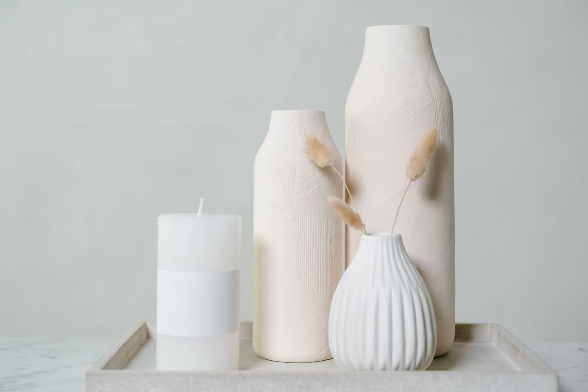 Elegant still life composition featuring ceramic vases and a candle in a minimalist style.