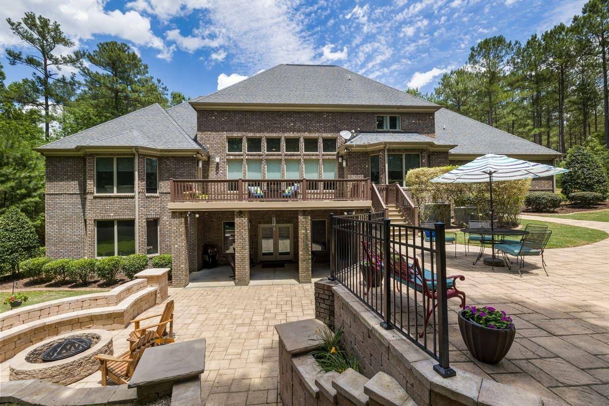 Luxury brick house featuring a large terrace, fire pit, and well-maintained garden.