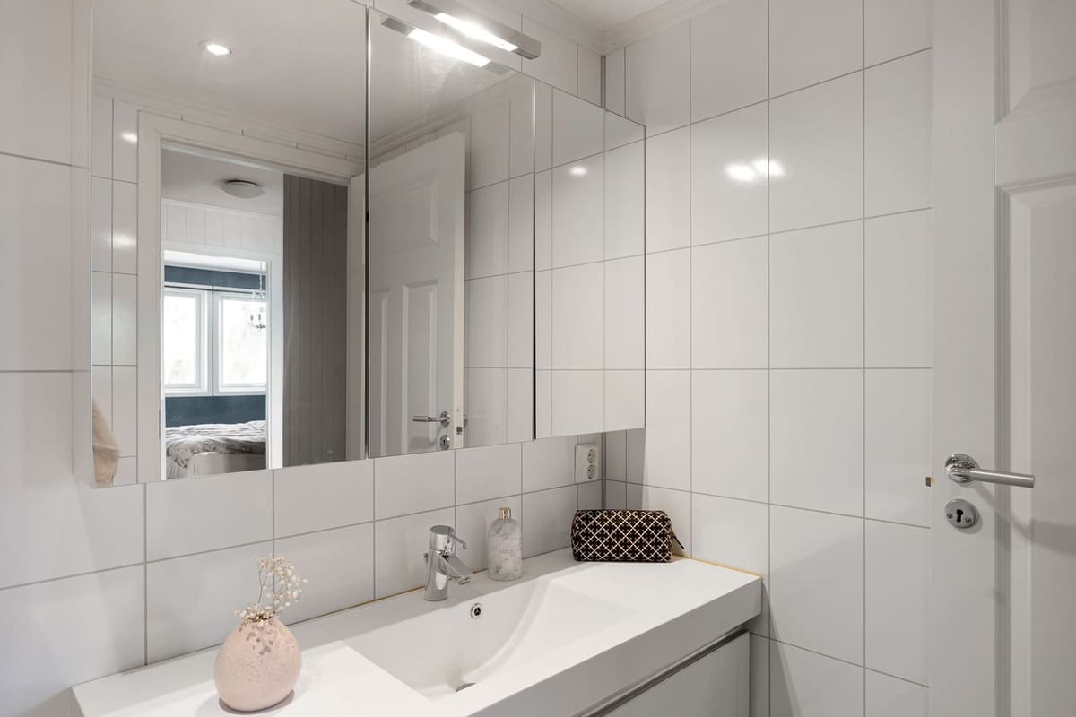 Sleek modern bathroom with white tiles, sink, and decorative elements.