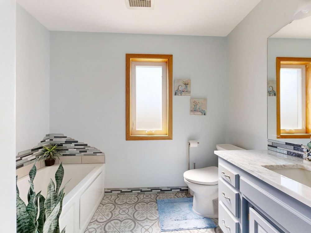 Bright modern bathroom featuring a tub, skylight, and elegant decor.
