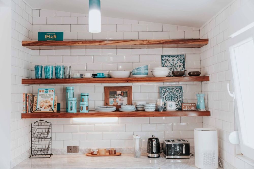 Stylish kitchen with open wooden shelves displaying tableware and decor.