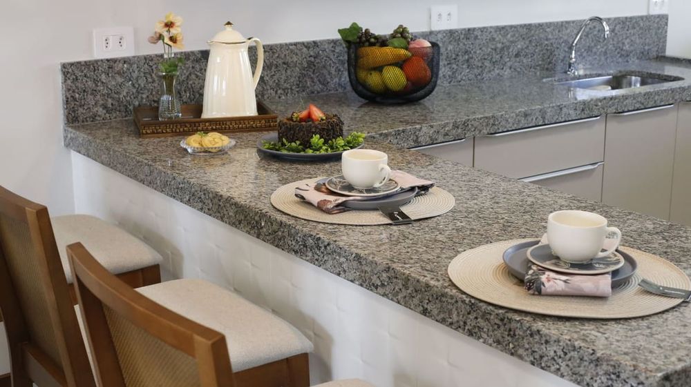 A cozy kitchen counter setup with two places set for breakfast, featuring cups and a cake.