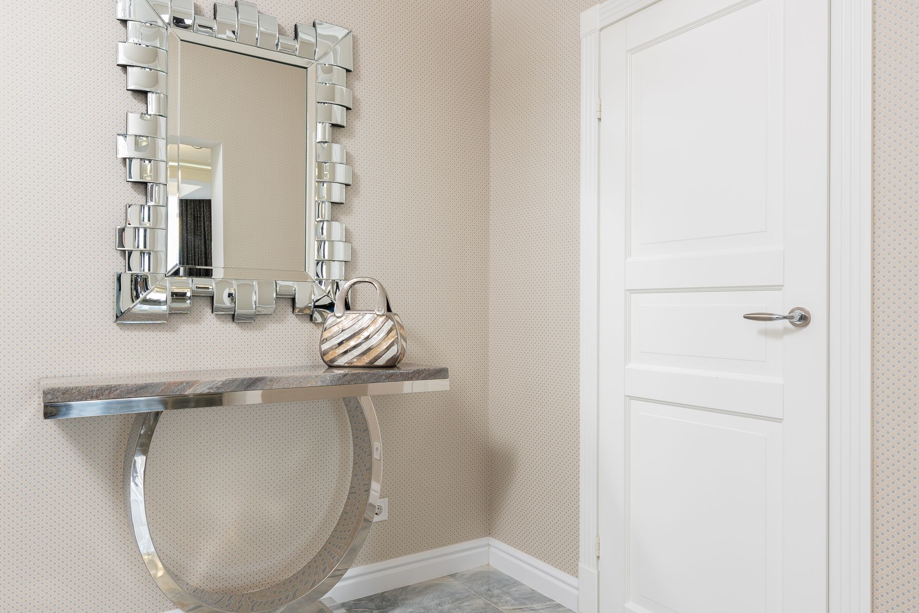 Creative design of hall with handbag on table under mirror in decorative frame against door at home