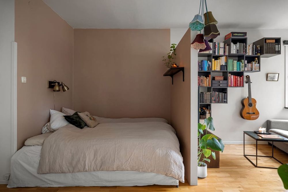 A contemporary bedroom with a double bed, guitar, and bookshelf, ideal for a cozy home setting.